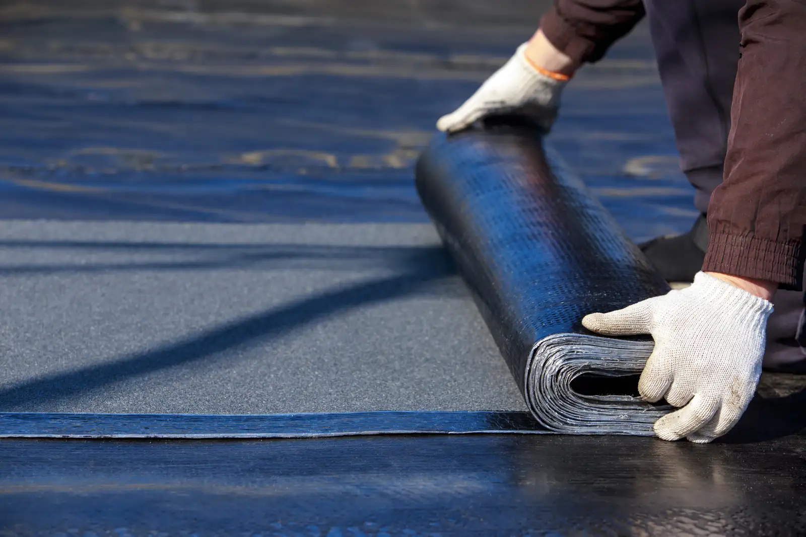 Roll of mineral-surfaced cap sheet being laid on a flat roof