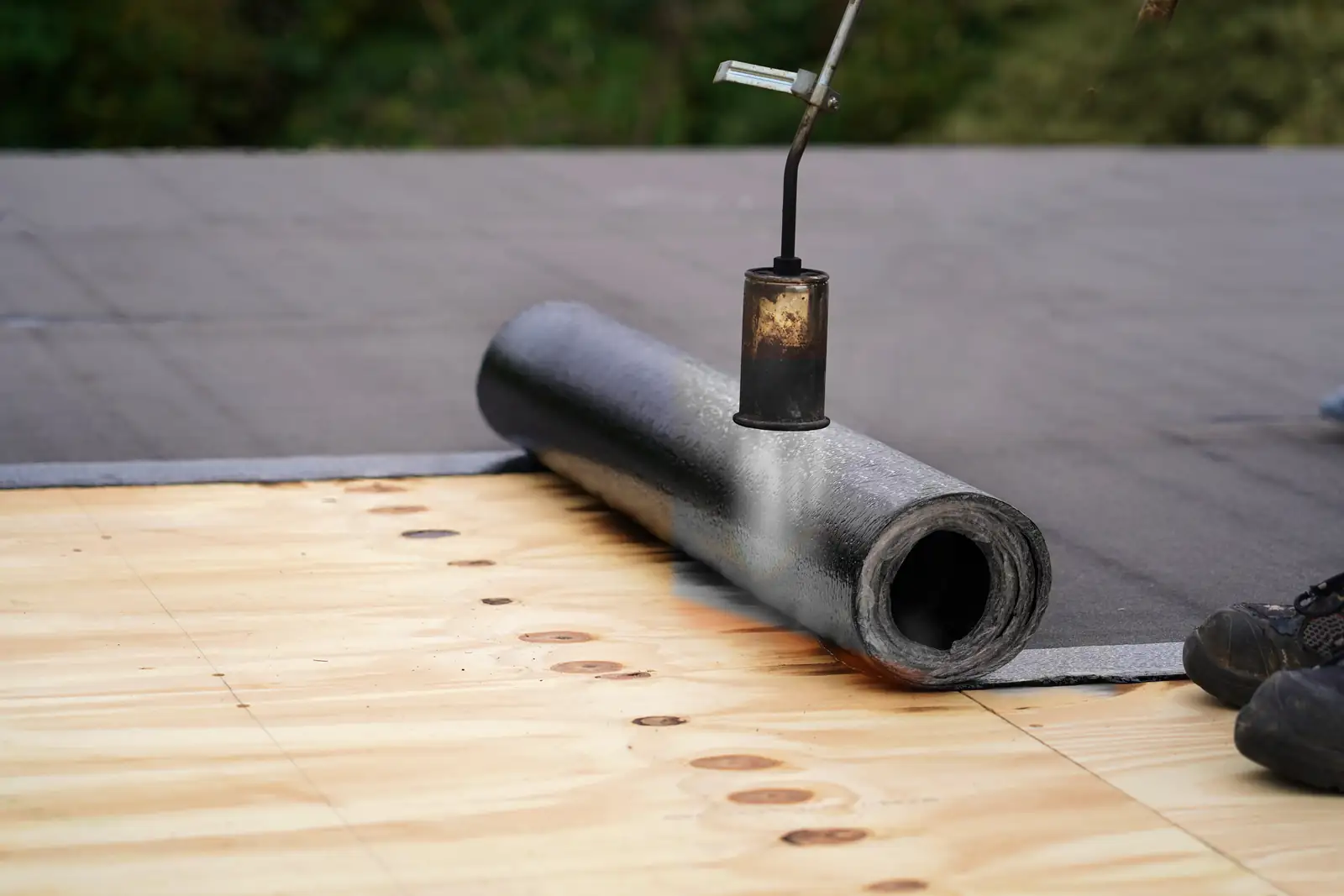 Felt roll and roofing torch on a new plywood flat roof deck